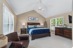 A bedroom with a bed, a ceiling fan, a dresser, a nightstand, and a window with blinds.