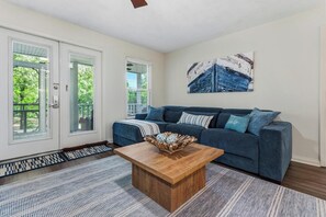 A living room with a blue sofa, a wooden coffee table, and a painting on the wall.