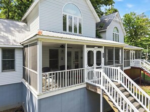 A two-story house with a covered porch and a staircase leading to the upper level.
