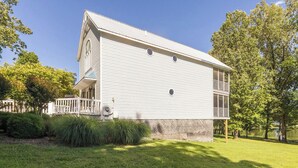 A two-story house with a porch, surrounded by trees and a grassy yard.