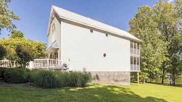 Ein zweigeschossiges Haus mit Veranda, umgeben von Bäumen und einem Rasengrundstück.