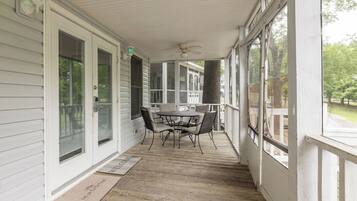 A covered porch with a table and chairs, a ceiling fan, and a view of the outdoors.