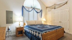 A bedroom with a wooden bed, a small bedside table, a lamp, and a window with curtains. - One Bedroom Bayside Condo (Grand Rivers)