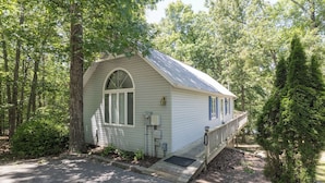 A small, single-story cabin with a porch, surrounded by trees. - One Bedroom Bayside Condo (Grand Rivers)