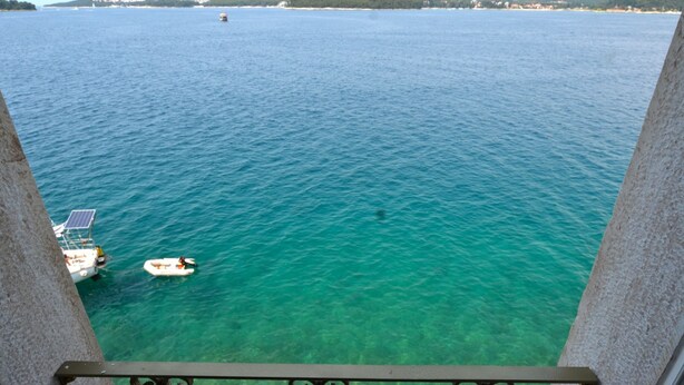 A balcony with a clear view of a calm sea, a small boat, and distant land. - Serene Sea View Rovinj Apartment (Rovinj)