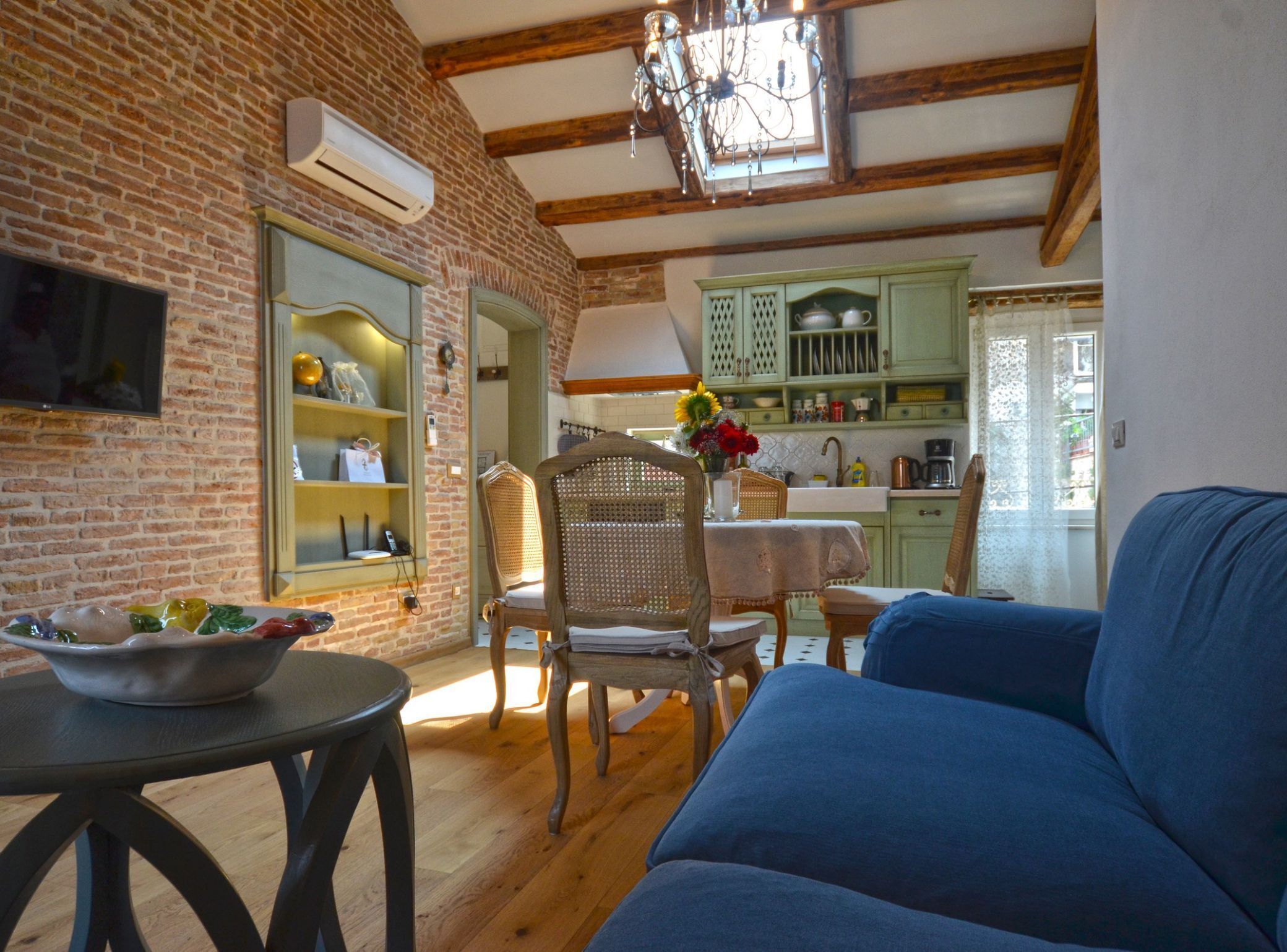Uma sala de estar aconchegante com um sofá azul, uma mesa de jantar de madeira e uma parede de tijolos.