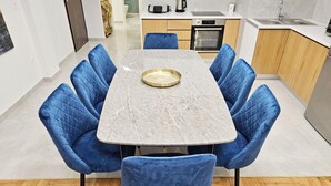 A modern dining area with a marble table and blue upholstered chairs. - Athens Prestige Suite Apartment (Athens)