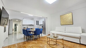 A modern living room with a white sofa, a glass coffee table, and blue chairs. - Athens Prestige Suite Apartment (Athens)