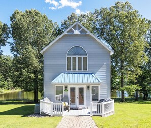A two-story house with a blue roof, a front porch, and a brick pathway leading to the entrance. - Executive Two Bedroom Pond View Condo (Grand Rivers)