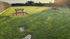 Un espace extérieur verdoyant avec des tables de pique-nique et une clôture en bois.