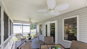 Une véranda abritée avec une table, des chaises et des ventilateurs de plafond.