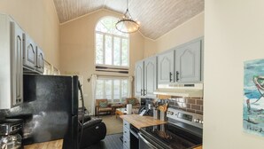 A kitchen with a black refrigerator, wooden countertop, and a large window.