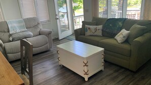 Ein Wohnzimmer mit einem beigefarbenen Sofa, einem weißen Couchtisch und einer Holzbank.