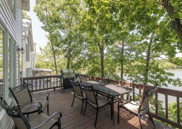 A wooden deck with a table and chairs, overlooking a lake. - Two Bedroom Bayside Condo (Grand Rivers)