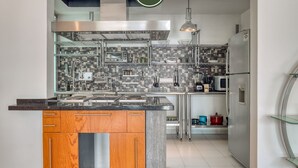 Una cocina moderna con una isla central, electrodomésticos de acero inoxidable y salpicadero de azulejos.