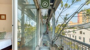 Habitación de hotel moderna con balcón de vidrio, una cama y vistas a la ciudad.