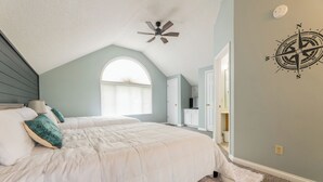 A bedroom with a bed, a ceiling fan, a compass wall decoration, and a window with blinds. - Two Bedroom Bayside Condo (Grand Rivers)