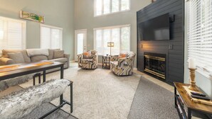 A living room with a fireplace, a sofa, two armchairs, a coffee table, and a bench. - Two Bedroom Bayside Condo (Grand Rivers)