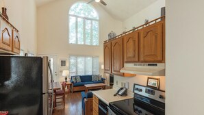 Una cocina con armarios de madera, un refrigerador, una estufa y una zona de comedor con sofá y mesa.