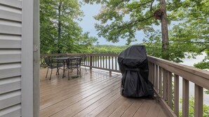 A wooden deck with a covered grill, a table, and chairs. - Two Bedroom Bayside Condo (Grand Rivers)