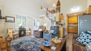 A cozy living room with a wooden coffee table, a blue patterned rug, and a staircase leading to a loft bedroom. - Two Bedroom Bayside Condo (Grand Rivers)