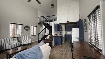 A spacious living area with a staircase leading to a kitchen and upper level.