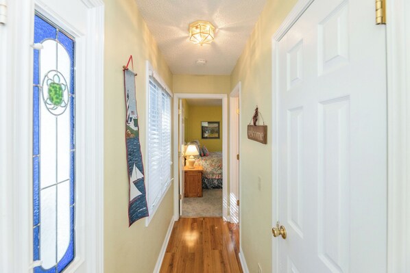 A hallway with a wooden floor, a blue-framed door, and a welcome sign.