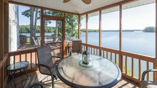 A covered outdoor area with a round glass table, chairs, and a ceiling fan.