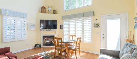 A living room with a fireplace, a TV, a dining table with chairs, a sofa, and a couch.