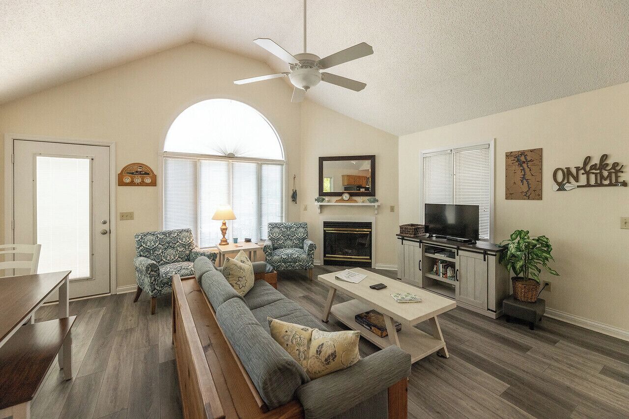 A spacious living room with a high ceiling, a fireplace, a television, and a dining area with a bench.