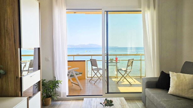Un salon moderne avec un balcon donnant sur une plage.