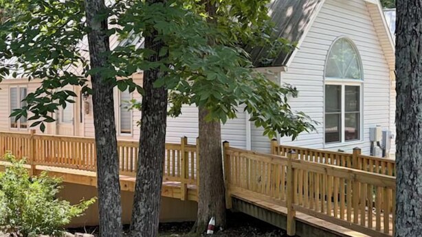 Una casa bianca con un patio in legno e un'ampia finestra.