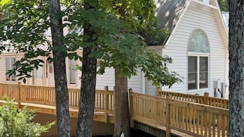 A white house with a wooden deck and a large window.