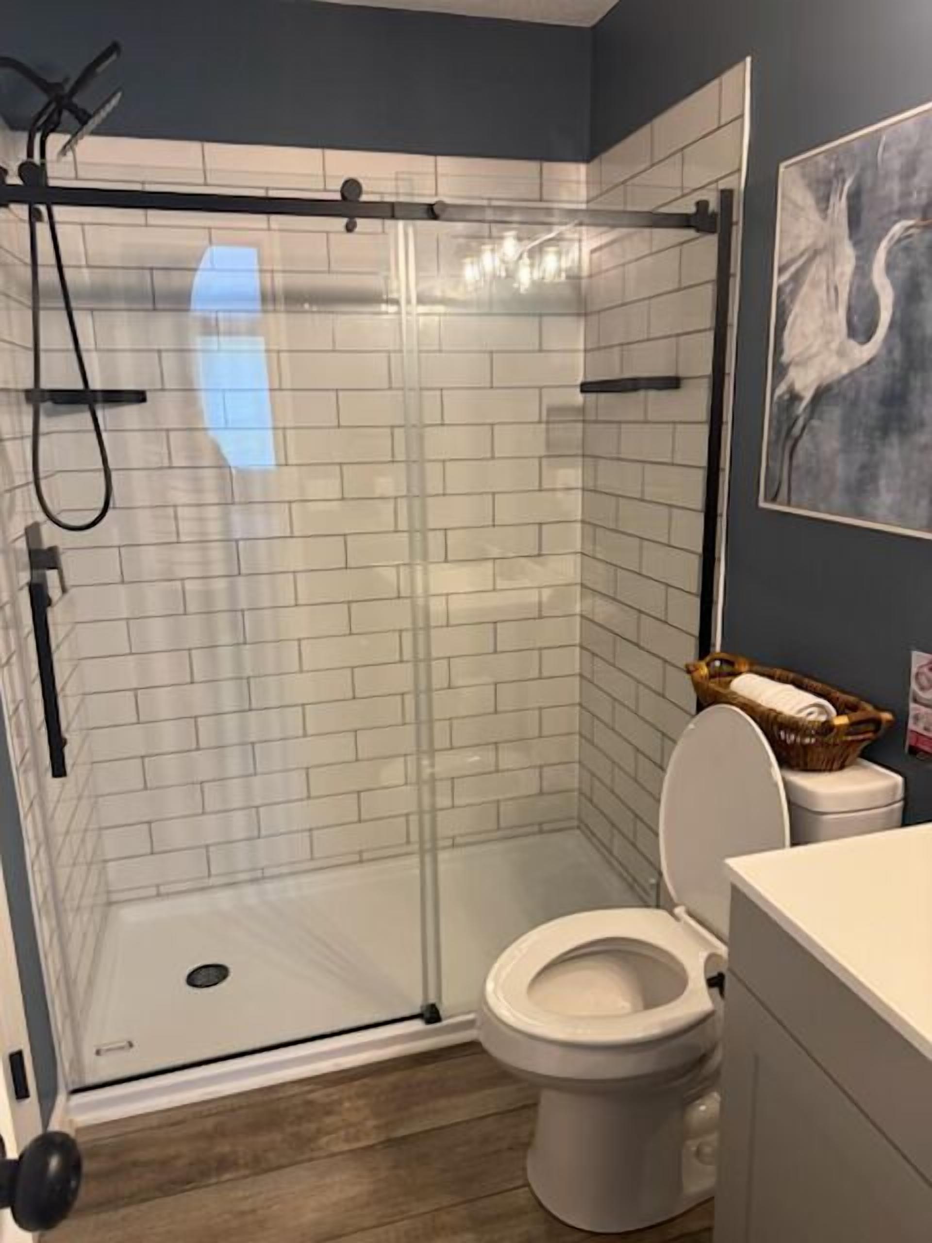 A bathroom with a glass-enclosed shower, a toilet, and a sink.