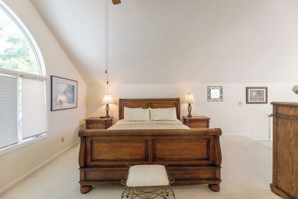 A bedroom with a large bed, two bedside tables with lamps, a wooden bench, and a window with blinds. - Two Bedroom Bayside Condo (Grand Rivers)