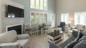 A spacious living room with a fireplace, a dining area, and a seating area with a sofa and chairs.