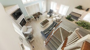 A spacious living room with a fireplace, a dining area, and a staircase.
