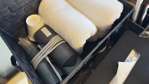 A black suitcase with two white towels, a black cylindrical object, and a white cylindrical object.