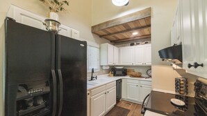 A kitchen with white cabinets, a black refrigerator, a stove, and a microwave. - Two Bedroom Bayside Condo (Grand Rivers)
