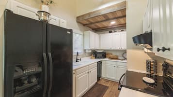 A kitchen with white cabinets, a black refrigerator, a stove, and a microwave.