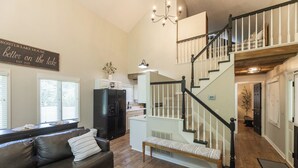 A spacious living area with a dark leather sofa, a bench, and a staircase leading to an upper level. - Two Bedroom Bayside Condo (Grand Rivers)