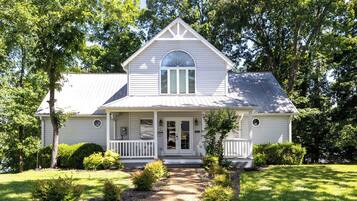 A two-story house with a front porch, a large arched window, and a gabled roof.