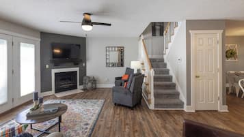 A living room with a fireplace, a television, and a staircase leading to another level.