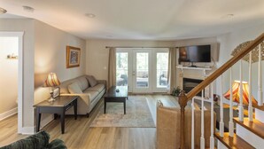 A living room with a sofa, a coffee table, a TV, and a staircase. - Four Bedroom Yacht Condo (Grand Rivers)