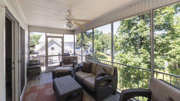 A covered porch with wicker furniture, a ceiling fan, and large windows offering a view of the outdoors. - Four Bedroom Yacht Condo (Grand Rivers)
