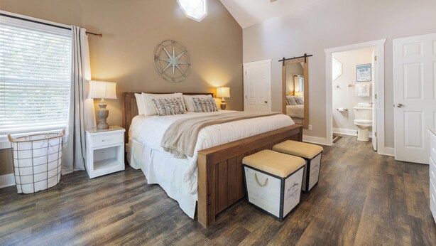 A bedroom with a large bed, bedside tables, a ceiling fan, and a view of the bathroom. - Four Bedroom Yacht Condo (Grand Rivers)