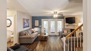 A living room with a grey sofa, a coffee table, and a TV mounted on the wall. - Four Bedroom Yacht Condo (Grand Rivers)