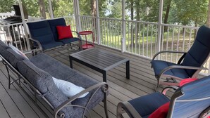 A covered outdoor deck with seating, a small table, and a grill. - Four Bedroom Yacht Condo (Grand Rivers)