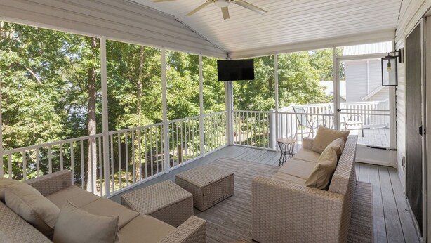 A covered porch with wicker furniture, a ceiling fan, and a TV mounted on the wall. - Four Bedroom Yacht Condo (Grand Rivers)