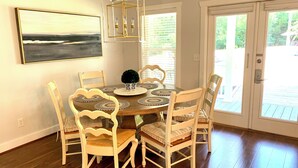 A dining area with a wooden table, six chairs, a chandelier, a potted plant, and a painting on the wall. - Four Bedroom Yacht Condo (Grand Rivers)